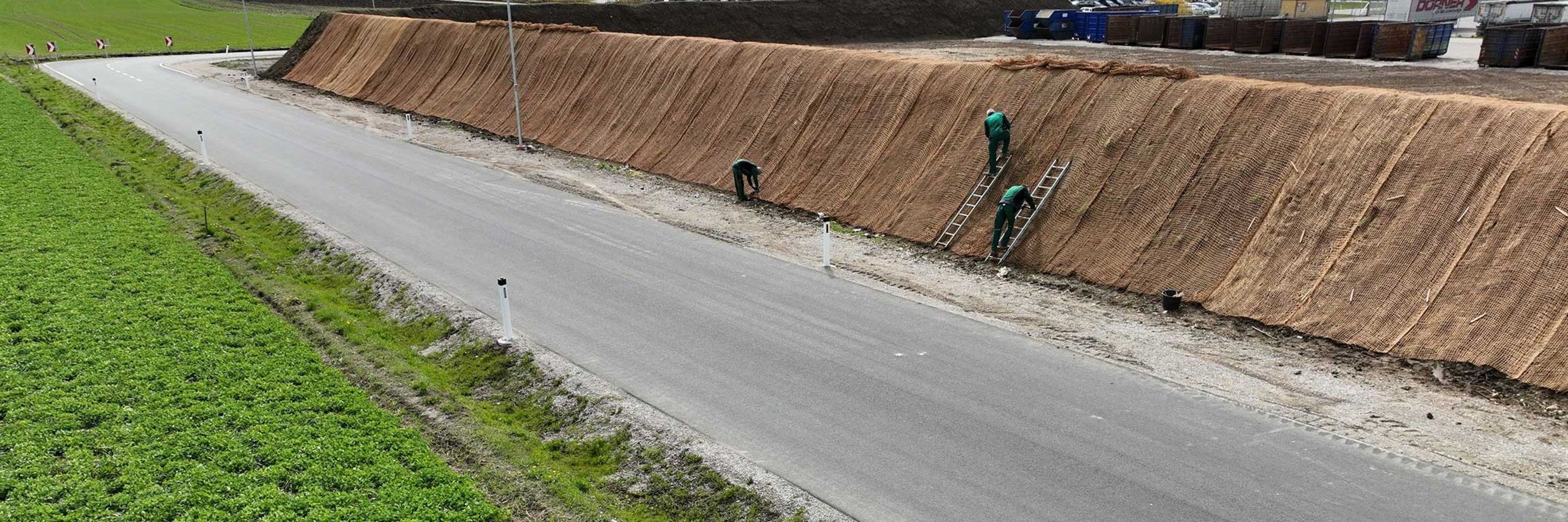 © Felbermayr/Nusime Biologisch abbaubares Kokosgeflecht und Arbeiter auf Leitern, die das Geflecht anbringen.