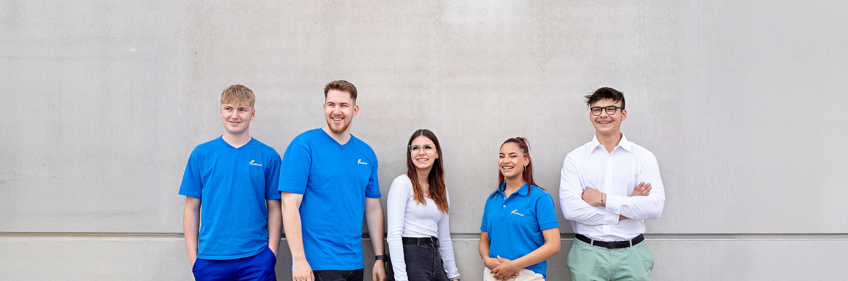 © andUP photo / social mediaKlammstrasse 3/12, 4020 Linz Lehre und Ausbildung bei Felbermayr: 5 Lehrlinge stehen lachend vor einer Betonwand